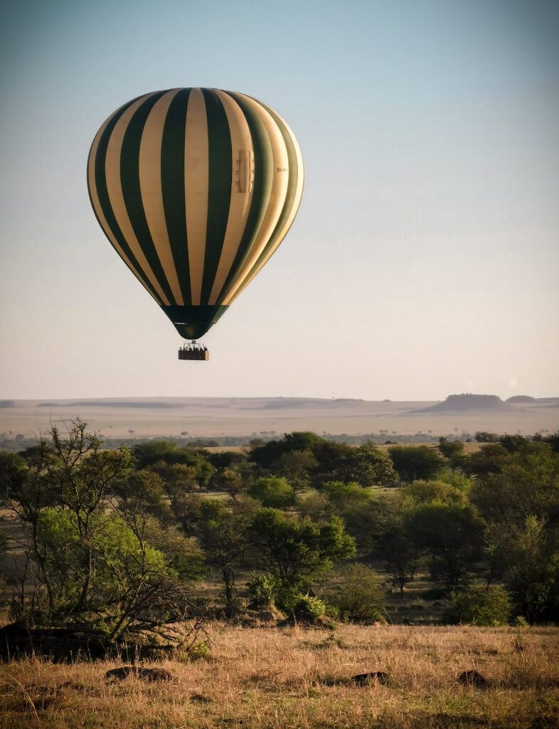 hot air balloon floating over serengeti at sunrise
